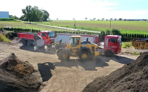 Firmengelände mit fahrenden LKW und Bagger